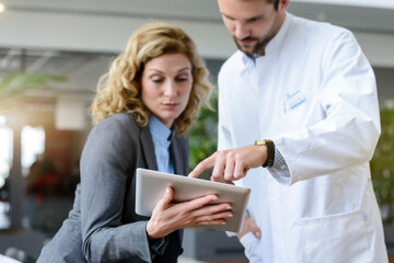 Businesswoman with tablet and doctor talking in hospital - obrazy, fototapety, plakaty