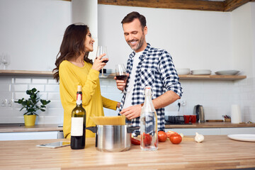 Affectionate couple in kitchen, preparing spaghetti toghether, drinking red wein