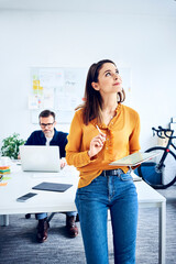 Businesswoman holding tablet in office with colleague in background