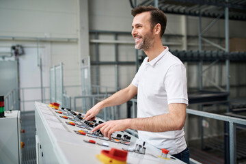 Smiling man operating control panel in a factory