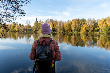 Mid adult woman with backpack looking at lake against sky in forest