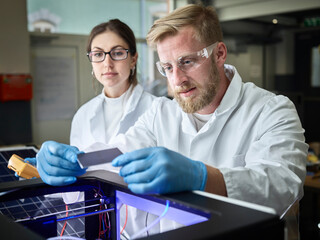 Two technicians working on solar cell in lab