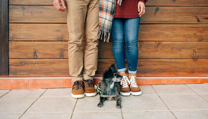 Low section of couple with dog standing in front of wooden wall - Powered by Adobe