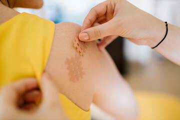 Physiotherapist applying cross tape on patient's shoulder