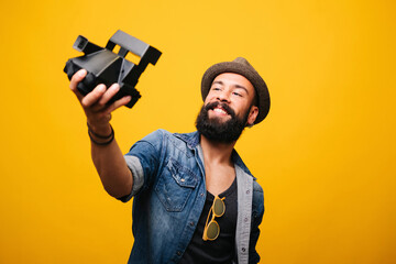 Bearded young man in studio taking selfie with instant camera