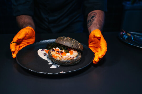Close-up of chef presenting a burger dish in restaurant kitchen