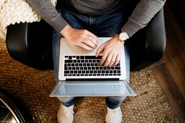 Man sitting at home, using laptop, close-up