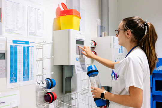 Female doctor using pneumatic tube system while standing in hospital