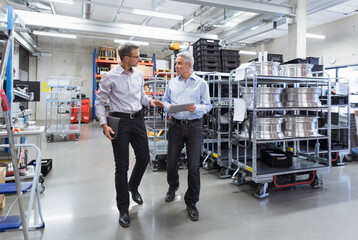 Two businessmen walking in factory hall