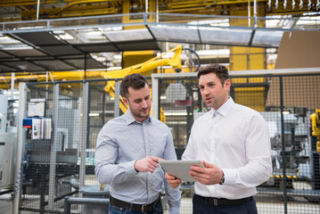 Two men with tablet talking in factory shop floor