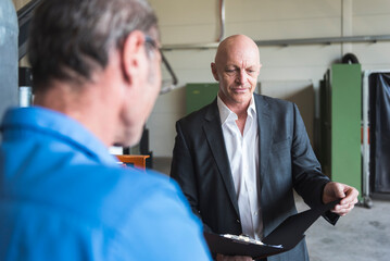 Two men with clipboard in factory