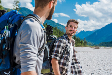 Germany, Bavaria, portrait of young hiker with backpack looking at his friend