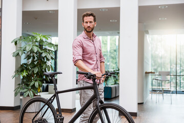 Portrait of man with bicycle in office