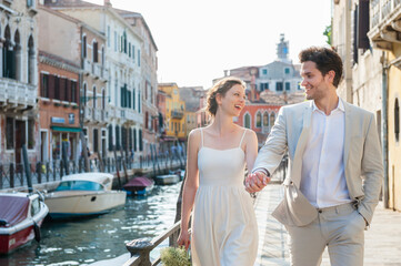 Fototapeta na wymiar Italy, Venice, happy bridal couple walking hand in hand at morning twilight