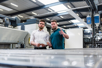 Two men with tablet discussing on factory shop floor