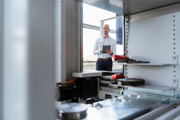 Businessman with tablet in company looking at product