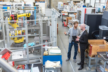 Two businessmen discussing in modern factory
