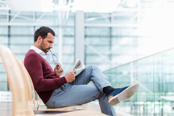 Obraz premium Businessman reading a newspaper in waiting hall