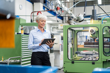 Senior businesswoman using tablet in a factory