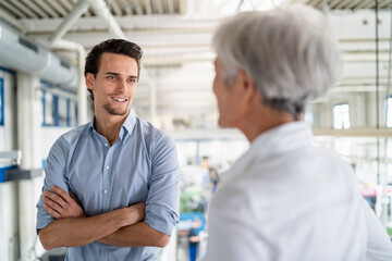 Smiling businessman talking to senior businesswoman in a factory