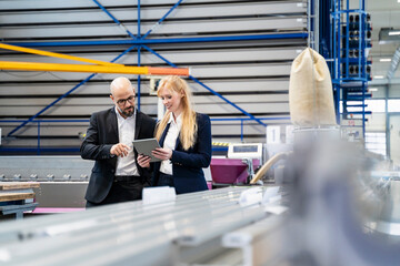 Businessman and businesswoman with tablet discussing in factory