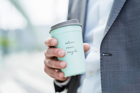 Close-up of businessman holding recycable takeaway coffee cup