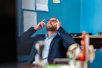 Businessman at desk in office balancing a pen on his nose