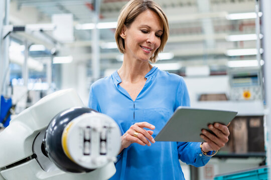 Businesswoman with tablet at assembly robot in a factory - Powered by Adobe