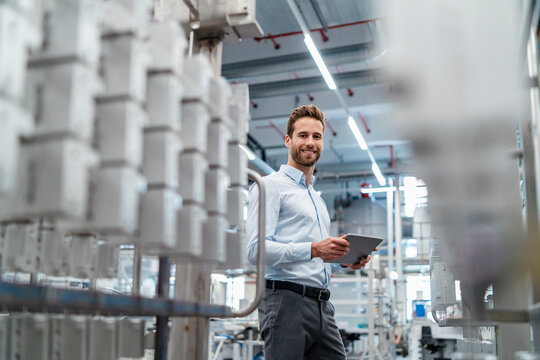 Portrait of a smiling businessman with tablet in a modern factory