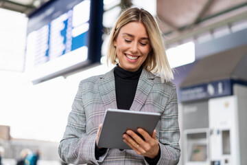 Smiling young businesswoman using tablet at the train station