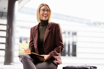 Smiling young businesswoman with notebook in the city