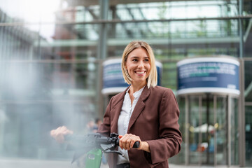 Happy young businesswoman with e-scooter in the city