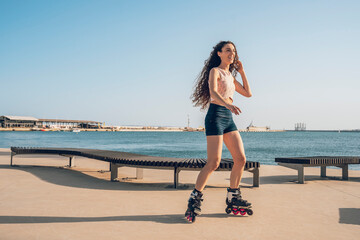 Young woman inline skating on promenade at the coast