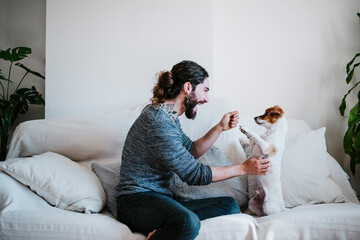 Happy man having fun while playing with dog at home