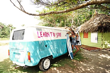 Portrait of woman with surfboard at van