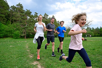 Cheerful family running on meadow against trees in forest