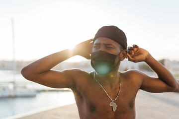 Black man with beanie putting on face mask