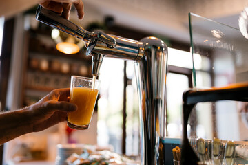 Bartender pouring beer in glass at cafe