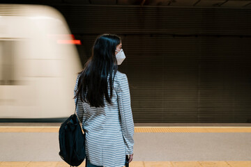 Female passenger waiting for her train at metro station during pandemic