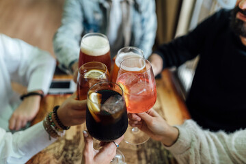 Friends hands toasting glasses at bar