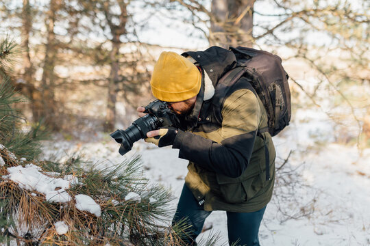 A man ventures into the snowy wilderness, documenting winter's beauty through his camera