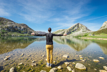 Fototapeta na wymiar Spain, Asturias, Picos de Europa National Park, man standing with raised arms at Lakes of Covadonga