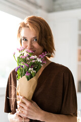Redheaded woman smelling bunch of flowers
