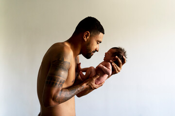 Affectionate father holding his crying nude newborn baby