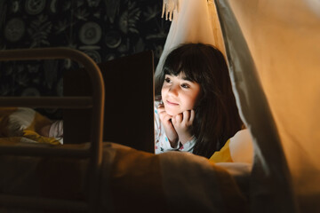 Portrait of smiling girl with lying on bed looking at laptop