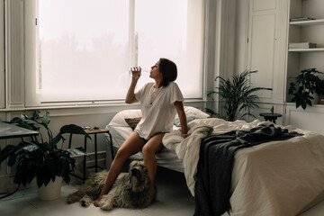 Mature woman sitting on bed in the morning drinking water