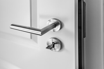 Slightly open wooden door with latch handle close-up