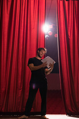 Barefoot actor standing on stage of theatre reading script