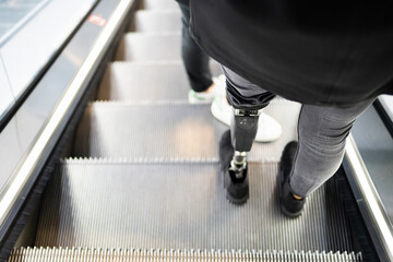Close-up of woman with leg prosthesis standing on escalator