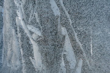 Background frozen water with fancy patterns. Ice texture. Cracks and bubbles inside frozen water.